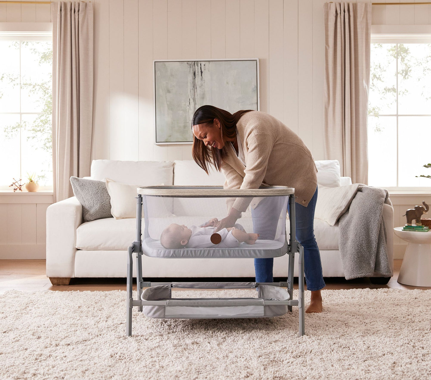 Mother placing her baby in the Maxi-Cosi® Iora Newborn Bassinet, highlighting the bassinet's spacious and comfortable sleeping area.