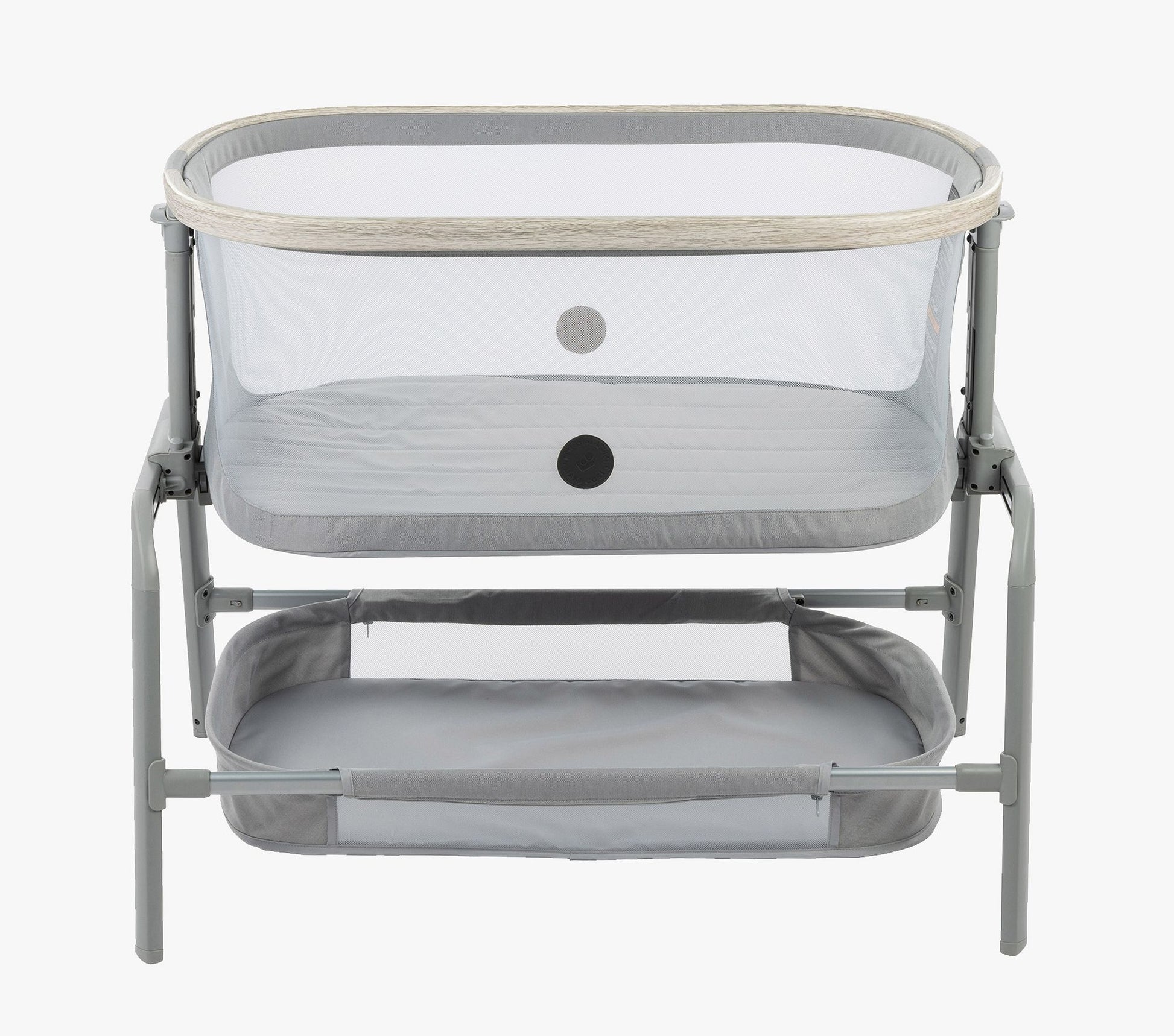 A side view of the Maxi-Cosi® Iora newborn Bassinet, showcasing its sleek design with breathable mesh sides and soft gray fabric. The bassinet includes a convenient lower storage shelf for easy access to baby essentials.